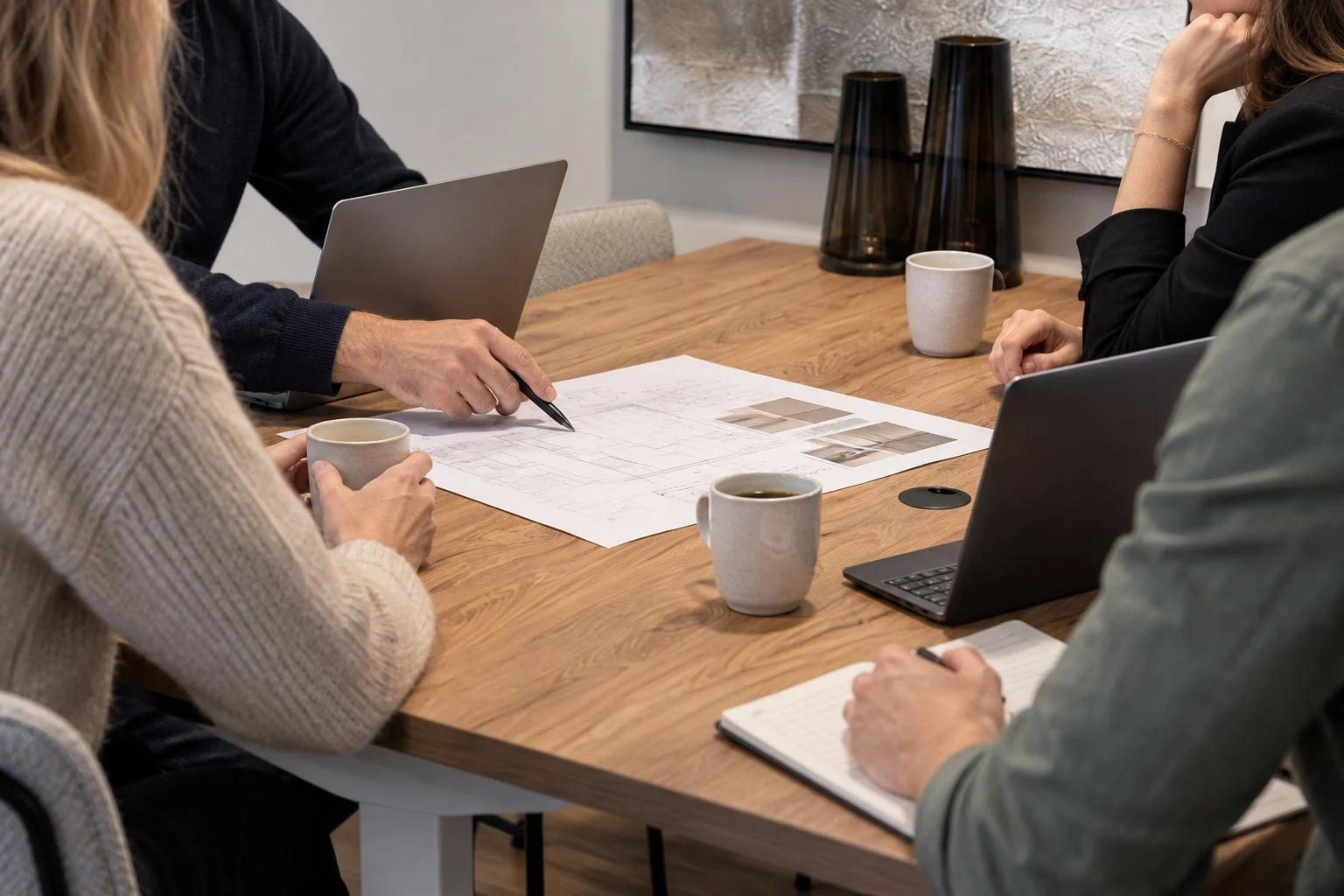 Professionals in overleg aan tafel, met laptops en een plan